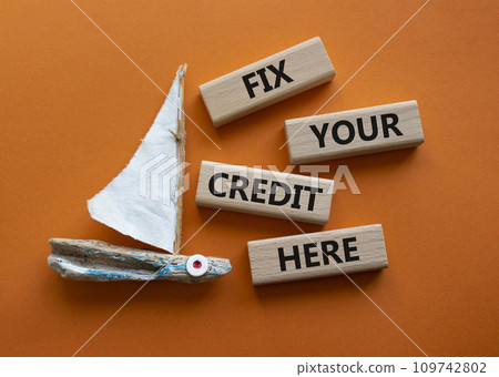 Fix your credit here symbol. Concept words Fix your credit here on wooden blocks. Beautiful orange background with boat. Business and Fix your credit here concept. Copy space. 109742802