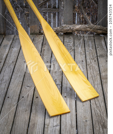 blades of wooden rowing oars against rustic, grunge wood deck 109743554