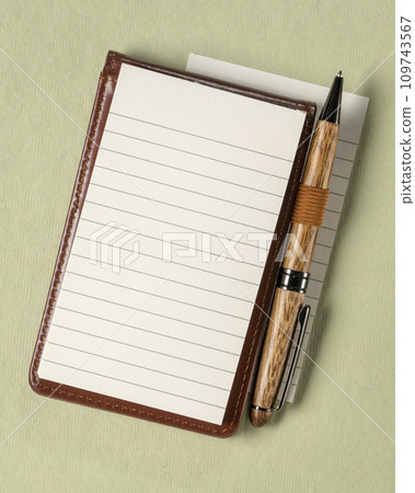 blank sheet of ruled paper in a small journal with a luxury pen against textured art paper 109743567