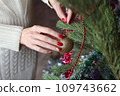 Female hands with red manicure and gold foil on the nails. Winter and Christmas time concept. Manicured woman's hands with Christmas decoration. 109743662