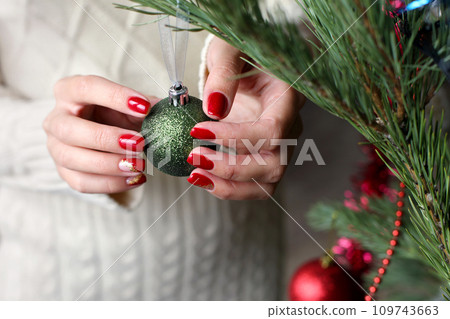 Female hands with red manicure and gold foil on the nails. Winter and Christmas time concept. Manicured woman's hands with Christmas decoration. Female hands with red manicure and gold foil on the nails. Winter and Christmas time concept. Manicured woman's hands with Christmas decoration. 109743663