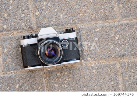 Old film photo camera lying on the pavement Old film photo camera lying on the pavement 109744176