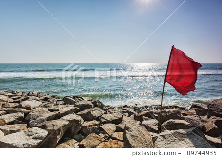 Red flag on rocky beach 109744935