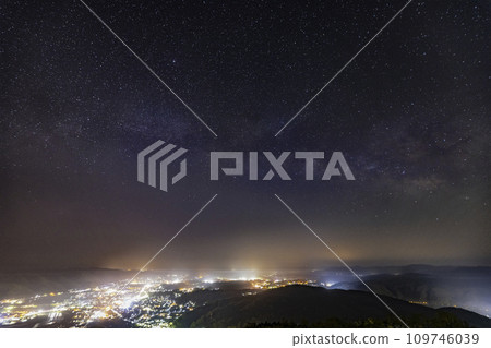 The Milky Way flows sideways through the night view of Miyoshi City, which is hazy with light fog. 109746039