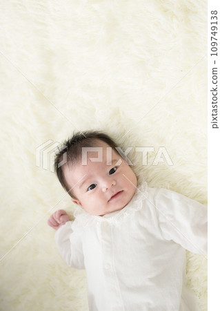 Smiling Asian (Japanese) baby wearing a baby dress smiling looking at the overhead camera Vertical 109749138