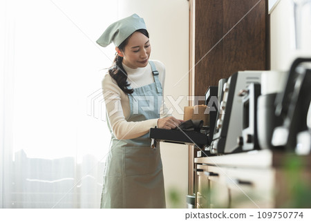 圍裙的女人從烤箱拿出蛋糕 109750774