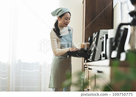 圍裙的女人從烤箱拿出蛋糕 109750775