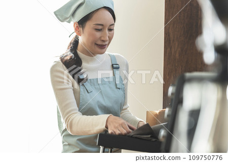 圍裙的女人從烤箱拿出蛋糕 109750776