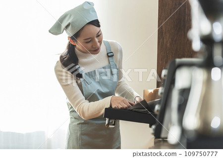 圍裙的女人從烤箱拿出蛋糕 109750777