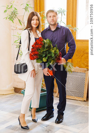 A couple of young men and women with a large bouquet of red roses. A couple of young men and women with a large bouquet of red roses. 109750956