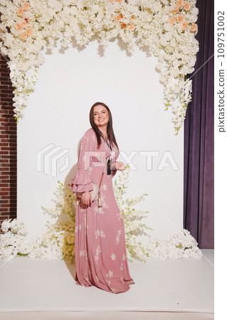 woman in a pink dress with a badge on the zone for taking photos at the party.  109751002