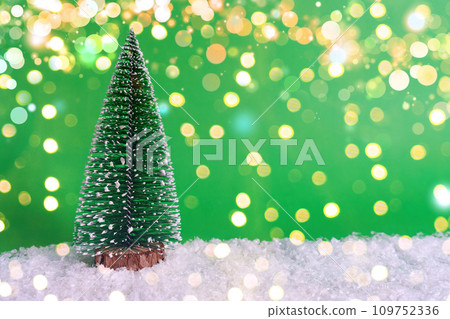 Snow-covered Christmas tree on snow and green background with bokeh. Christmas banner concept, card with mark for copy 109752336