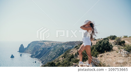 Woman summer travel sea. Happy tourist enjoy taking picture outdoors for memories. Woman traveler posing over sea bay surrounded by volcanic mountains, sharing travel adventure journey 109753665
