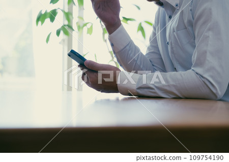 A middle-aged man gets shocked when he looks at his smartphone A middle-aged man gets shocked when he looks at his smartphone 109754190