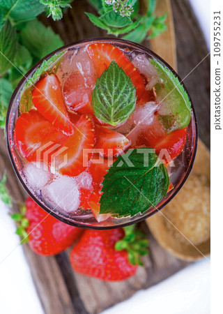 cocktail with fresh strawberries, mintand ice cubes over old white wooden table. cocktail with fresh strawberries, mintand ice cubes over old white wooden table. 109755231