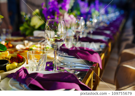 Beautiful festive table setting with flowers and purple napkins. Beautiful festive table setting with flowers and purple napkins. 109755679