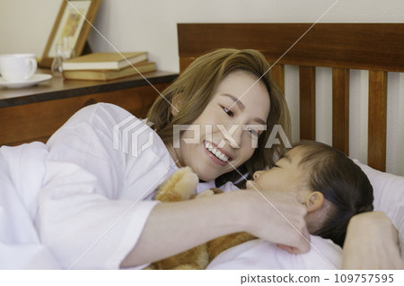 Young mom lulling her girl to sleep on the bed Young mom lulling her girl to sleep on the bed 109757595