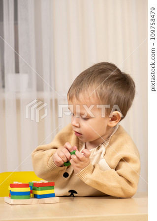 A two-year-old boy plays with wooden toys to develop logic and motor skills A two-year-old boy plays with wooden toys to develop logic and motor skills 109758479