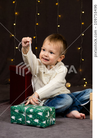 Little two-year-old boy opens Christmas gifts at home Little two-year-old boy opens Christmas gifts at home 109758496