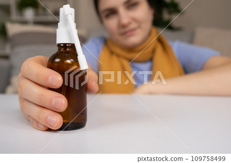 A bottle of medicine to treat a sore throat and cough in a patient's hand. A bottle of medicine to treat a sore throat and cough in a patient's hand. 109758499