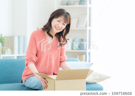 Middle-aged woman receiving luggage at home Middle-aged woman receiving luggage at home 109758608