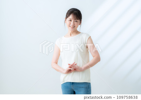 A middle-aged woman doing skin care against a white background A middle-aged woman doing skin care against a white background 109758638