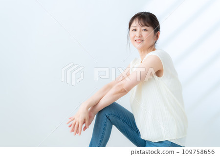 A middle-aged woman doing skin care against a white background A middle-aged woman doing skin care against a white background 109758656