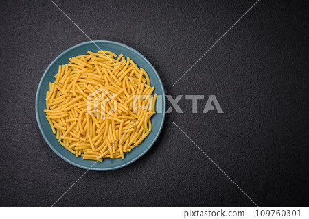 Raw whole grain wheat pasta with salt and spices in a ceramic plate 109760301