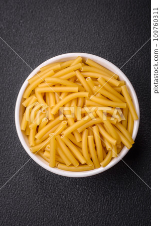 Raw whole grain wheat pasta with salt and spices in a ceramic plate Raw whole grain wheat pasta with salt and spices in a ceramic plate 109760311
