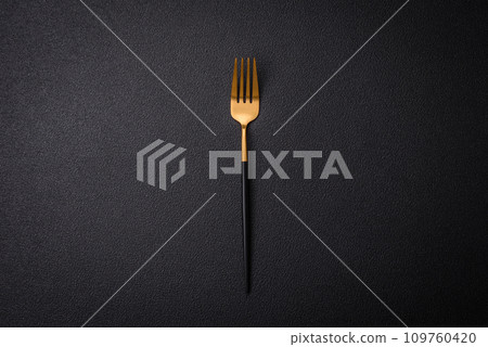 Kitchen fork made of steel on a dark textured background Kitchen fork made of steel on a dark textured background 109760420