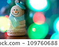 Snowman macaron dessert decorated with hat and scarf against colorful lights and bokeh background. Merry Christmas and Happy New Year festive concept 109760688
