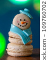 Snowman macaron dessert decorated with hat and scarf against colorful lights and bokeh background. Merry Christmas and Happy New Year festive concept 109760702