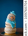 Snowman macaron dessert decorated with hat and scarf against blue background. Merry Christmas and Happy New Year festive concept 109760704