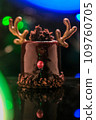 Chocolate reindeer cake with brown cream frosting decorated with antlers against colorful lights and bokeh background. Merry Christmas and Happy New Year festive concept 109760705