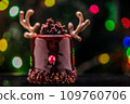 Chocolate reindeer cake with brown cream frosting decorated with antlers against colorful lights and bokeh background. Merry Christmas and Happy New Year festive concept 109760706