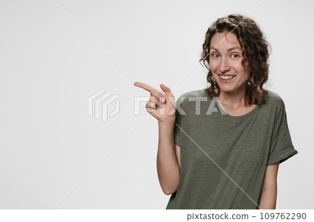 Portrait of happy young woman indicates with index finger at blank copy space 109762290