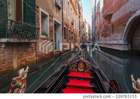 Experience the timeless charm of Venice with this serene image of a traditional gondola on a peaceful canal. Discover the beauty of Italy's iconic city. 109763153