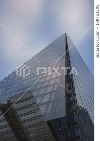 Low angle view of The Shard in city. Financial office building with blue sky in background. Glass windows on modern structure in London. 109763205
