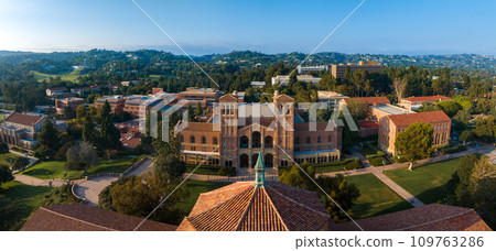 Aerial view of UCLA campus featuring classical architecture, red-brick buildings, green spaces, and a distinctive domed structure under a clear blue sky. Aerial view of UCLA campus featuring classical architecture, red-brick buildings, green spaces, and a distinctive domed structure under a clear blue sky. 109763286