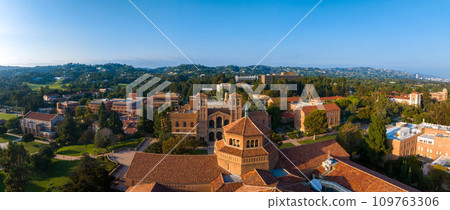 Aerial view of UCLA campus in Westwood, Los Angeles, featuring red-brick, Gothic, and modern buildings amidst green lawns and trees on a sunny day. 109763306