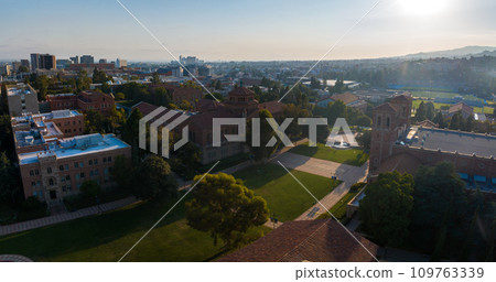 Aerial view of a university campus at sunrise or sunset, featuring historic red-brick buildings, modern architecture, lush greenery, and a city backdrop under a clear sky. Aerial view of a university campus at sunrise or sunset, featuring historic red-brick buildings, modern architecture, lush greenery, and a city backdrop under a clear sky. 109763339
