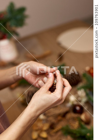 Woman making Christmas arrangement with fir branches. craft handmade decor. 109763901