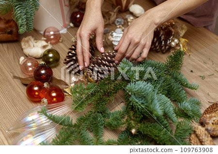 Woman making Christmas arrangement with fir branches and pine cones. craft handmade decor. Woman making Christmas arrangement with fir branches and pine cones. craft handmade decor. 109763908