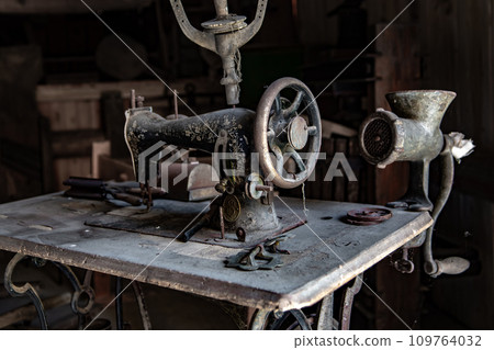 Dusty Vintage Manual Sewing Machine And Kitchen Tools On Table In Old Barn Dusty Vintage Manual Sewing Machine And Kitchen Tools On Table In Old Barn 109764032