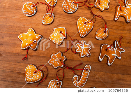 Wooden background with lots of gingerbread Christmas gingerbread in the shape of a house, heart. Deer. star, christmas tree toy, ball with white glaze. High quality photo 109764536