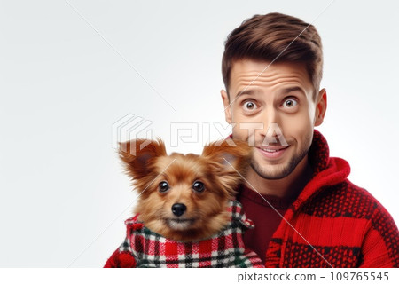 white man in warm, cozy red sweater hugging his beloved purebred pomeranian chihuahua dog. Smiles in surprise. Together with friend. Cozy and atmospheric photo. On white background with copy space white man in warm, cozy red sweater hugging his beloved purebred pomeranian chihuahua dog. Smiles in surprise. Together with friend. Cozy and atmospheric photo. On white background with copy space 109765545