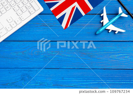 Great Britain flag and toy plane on blue wooden background Great Britain flag and toy plane on blue wooden background 109767234