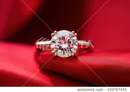 Sparkling diamond engagement ring on a red background. Symbolizes love and devotion. Jewelry. Large brilliant. Close up. Elegant wedding ring. presentation, poster, banner, brochure of jewelry store 109767445