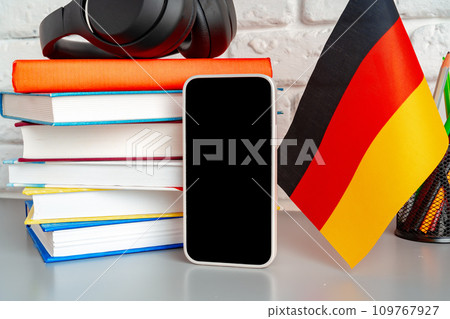 Stack of books and flag of Germany on desk. German language learning concept 109767927