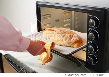 Woman's hands taking fresh bakery out of mini oven 109768055